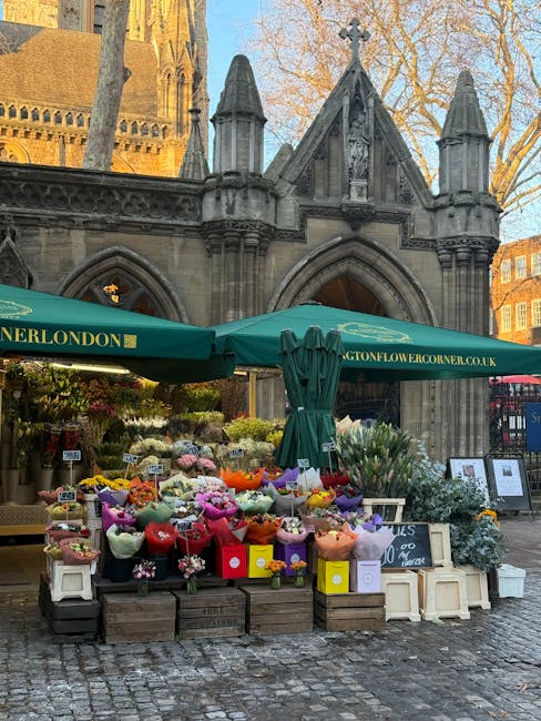 An outdoor flower market set up in front of a historic stone Gothic-style building with pointed arches and decorative spires, featuring a variety of fresh floral bouquets wrapped in colorful paper and